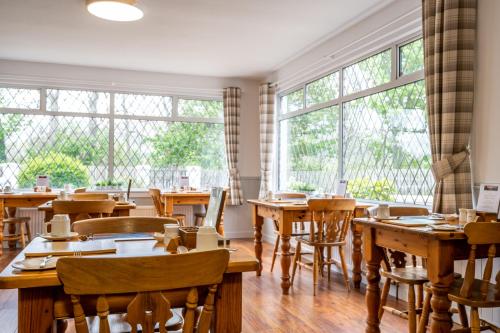 a restaurant with wooden tables and chairs and windows at Riverside in Ullapool