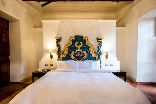 a bedroom with a large bed with a blue and gold headboard at Palacio Manco Capac by Ananay Hotels in Cusco