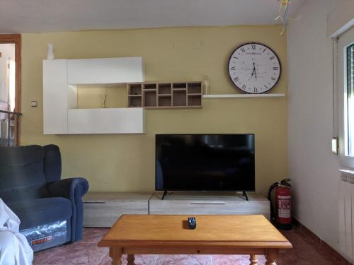 a living room with a tv and a clock on the wall at EL PINAR DE BARDENA in Carcastillo