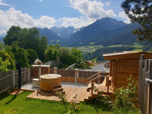 a backyard with a wooden deck with a hot tub and mountains at Chalet Gletscherblick Stubai in Mieders
