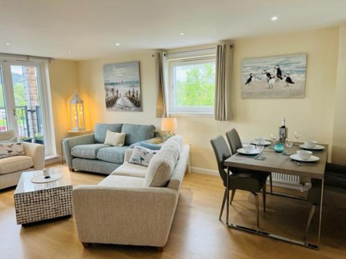 a living room with a couch and a table at Riverside View Penthouse in Balloch, Loch Lomond in Balloch