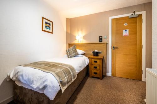 a small bedroom with a bed and a wooden door at Riverside in Ullapool