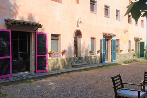 a building with pink doors and a bench in front of it at Masia Sagués in Poblet