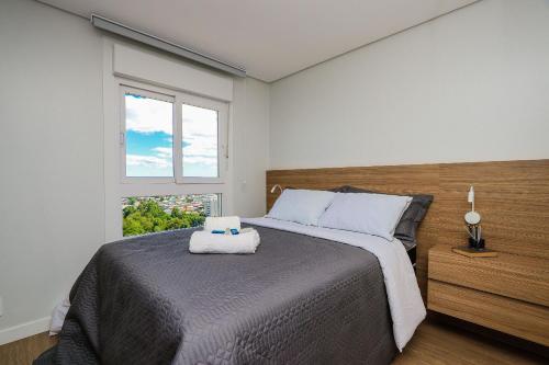 een slaapkamer met een groot bed en een raam bij Wynn Residencial - 1002 in Caxias do Sul