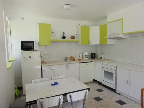 une cuisine avec des armoires blanches et une table avec des chaises dans l'établissement Appartement T1 meublé haut vallespir le Tech, à Le Tech