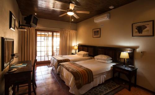 a bedroom with two beds and a ceiling fan at Sunbird Lodge in Phalaborwa
