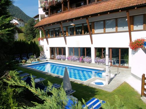 a villa with a swimming pool in front of a building at Hotel Montana in Arzl im Pitztal