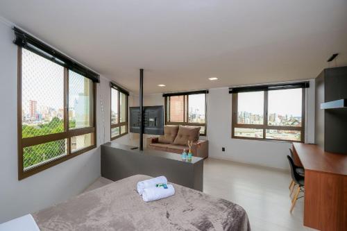 a bedroom with a bed and a couch and windows at Paseo Del Molino - 703 in Caxias do Sul