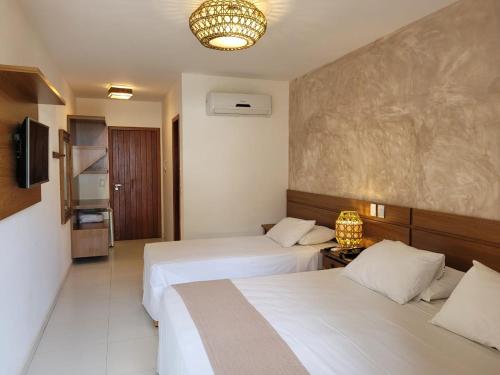 a hotel room with two beds and a television at Aquarela Praia Hotel in Arraial d'Ajuda