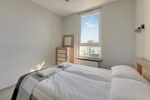 a white bedroom with a bed and a window at Wave Apartments - Solvo 2 in Gdańsk