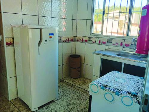 a kitchen with a white refrigerator and a sink at Pousada Jesus Misericordioso in Aparecida