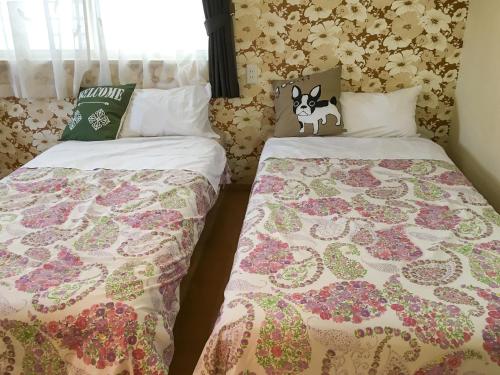 two beds in a room with flowers on the wall at Pension Marinetown Aratta Vacation STAY 13299 in Gaja