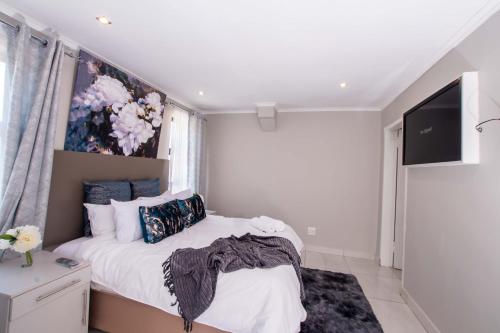 a bedroom with a bed with a painting on the wall at Prestigious Apartments in Fourways