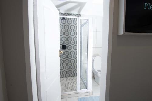 a bathroom with a shower with a toilet and a mirror at Prestigious Apartments in Fourways