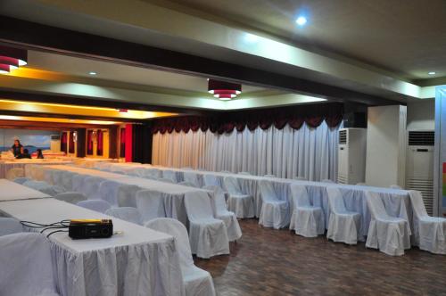 a banquet hall with white tables and white chairs at Maharajah Hotel in Angeles