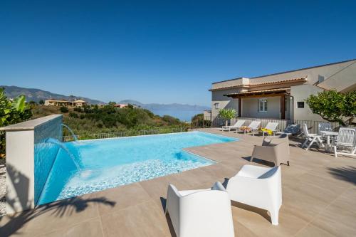 una piscina con sillas blancas y una casa en Villa DellAcqua, en Alcamo Marina