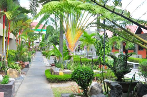 a garden with palm trees and a sidewalk at Maharajah Hotel in Angeles