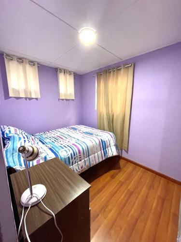 a bedroom with a bed and a desk and purple walls at Mi Pueblito Lodge in Huancayo