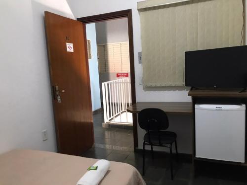 a room with a bed and a desk and a television at HOTEL BELA VISTA NOVA ODESSA in Nova Odessa
