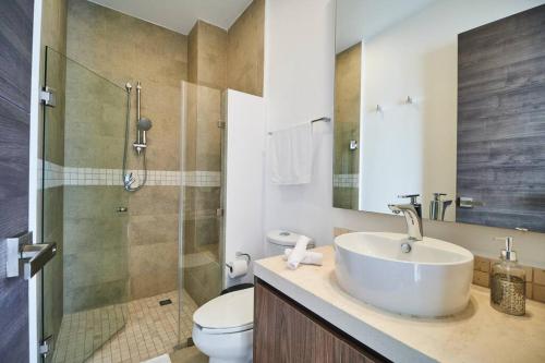 Un baño con lavabo, inodoro y ducha. en Macbeth - Rooftop with Jacuzzi & Beach Club Access, en Tulum