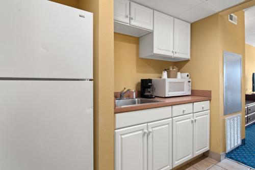 a kitchen with white cabinets and a sink and a refrigerator at Bonita Beach Hotel in Ocean City