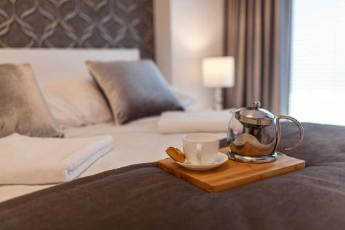 a tray with a tea kettle and a cup on a bed at Apartament Greno Kielce in Kielce