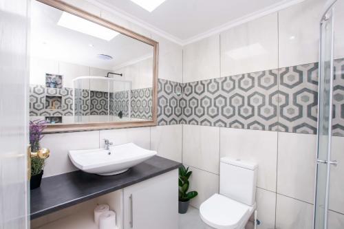 a bathroom with a sink and a toilet and a mirror at Prestigious Apartments in Fourways