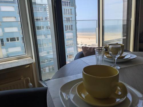 a coffee cup on a table in front of a window at Studio Sun south- seaview-sea at 15meter-Ostend in Ostend