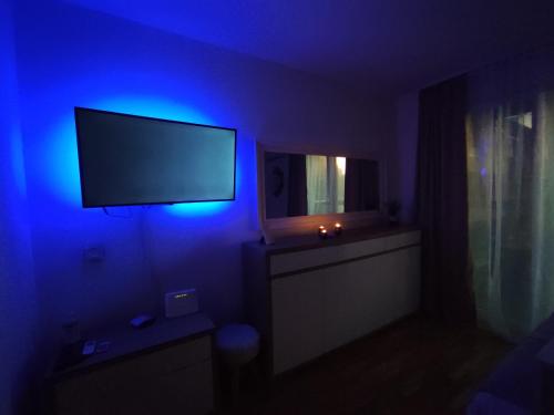 a dark room with a tv and a blue light at Sky Way Studio Apartment in Sarajevo