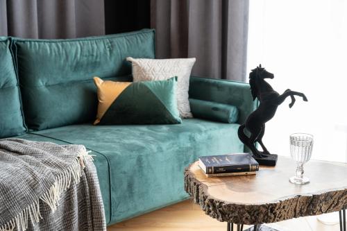 a green couch with a cat statue on a table at Wrota Chałubińskiego in Zakopane