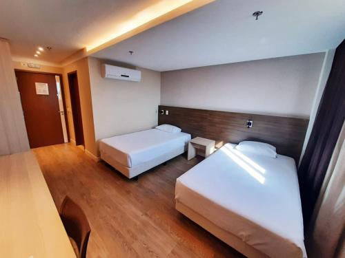 a hotel room with two beds and a table at Ibiza Plaza Hotel in Anápolis