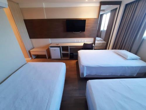 a hotel room with two beds and a television at Ibiza Plaza Hotel in Anápolis