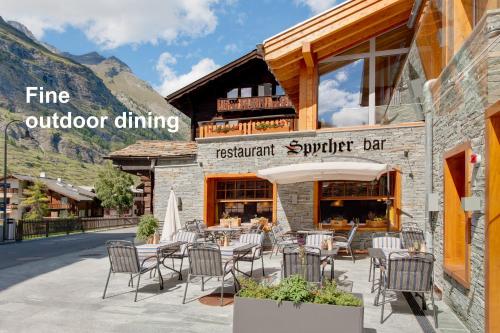 a restaurant with tables and chairs outside of a building at Hotel Aristella Swissflair in Zermatt