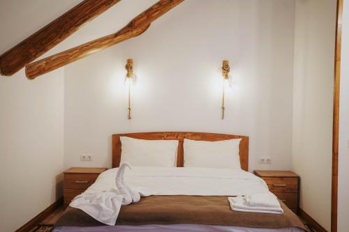a bedroom with a bed with white sheets and pillows at Hanul lui Mujdei in Vatra Dornei