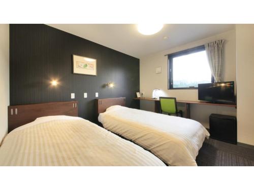 um quarto de hotel com duas camas e uma secretária em HOTEL COONEL INN - Vacation STAY 33523v em Susono