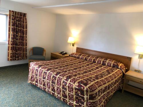 Habitación de hotel con cama y silla en DEEPWELL MOTEL, en Owego