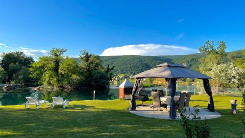 a gazebo with chairs and tables next to a lake at Apartman Deluxe Una Holiday in Bihać