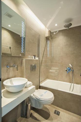 a bathroom with a sink and a toilet and a tub at Fedriades Delphi Hotel in Delfoi