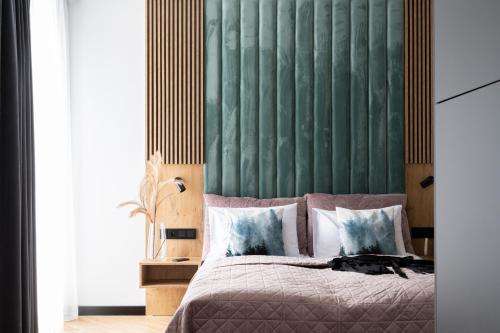 a bedroom with a bed with a green headboard at Wrota Chałubińskiego in Zakopane