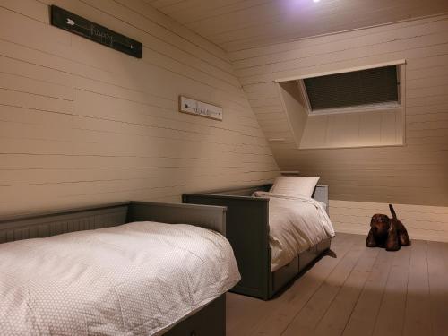 a bedroom with two beds and a teddy bear sitting on the floor at La Cense du Noir Jambon in Silly