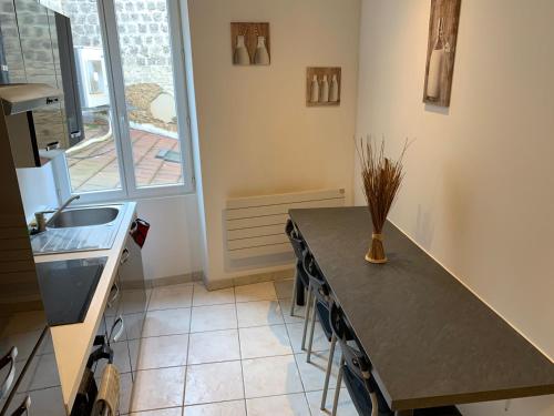 une cuisine avec une table, un évier et une fenêtre dans l'établissement Appartement de la nation 1, à La Tour-du-Pin