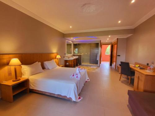 a bedroom with a large white bed and a desk at La Maison Des Oliviers in Marrakesh