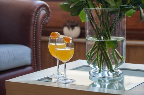 two glasses of orange juice and a vase on a table at Fedriades Delphi Hotel in Delfoi
