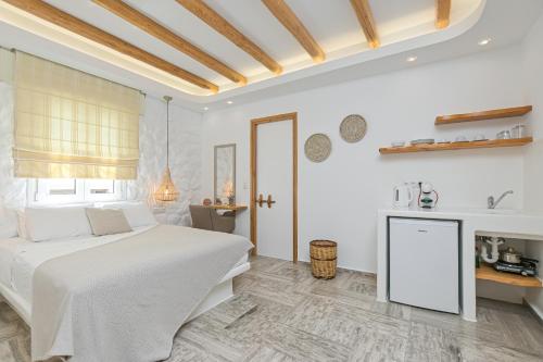 a white bedroom with a bed and a table at Blue Sky Summer in Naxos Chora