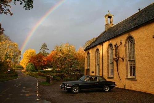 a black car parked in front of a building with a rainbow at Highland Lodge in Kilmorack