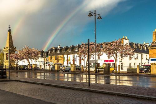 a rainbow in the sky over a city with a street at Highland Lodge in Kilmorack
