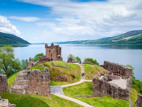 a castle on a hill next to a body of water at Highland Lodge in Kilmorack