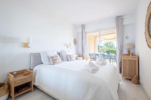- une chambre blanche avec un grand lit blanc et un balcon dans l'établissement SERRENDY  RARE !  Superbe 3 pièces avec jardin & vue sur la mer , à Cannes