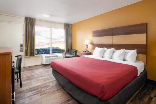 um quarto de hotel com uma cama grande e uma janela em Americana Inn a Travelodge by Wyndham em Pigeon Forge