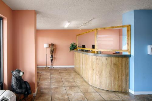 a lobby with a counter in a room with orange walls at Americana Inn a Travelodge by Wyndham in Pigeon Forge